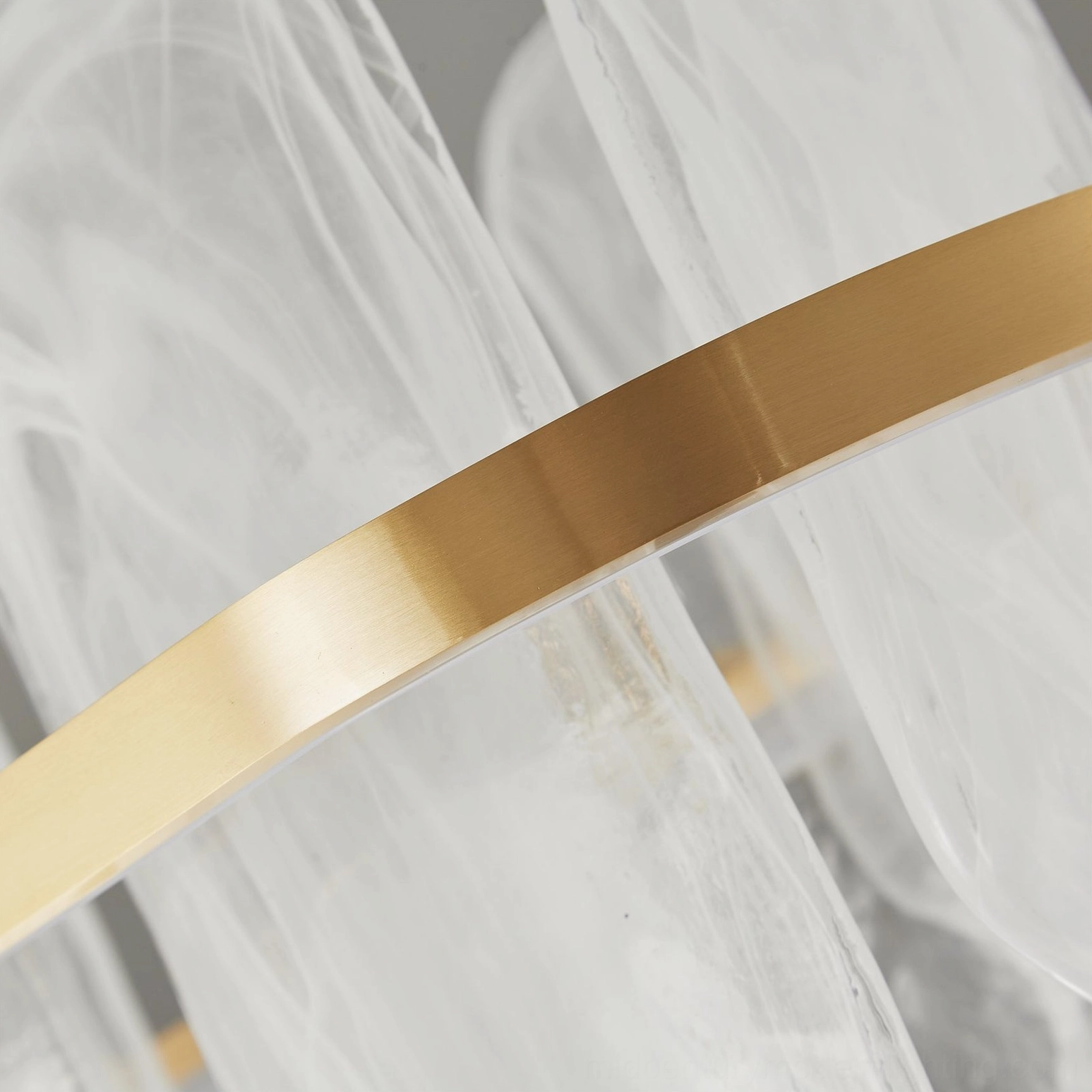 Close-up macro detail of brushed brass metal trim and frosted cloud glass texture on Mille chandelier