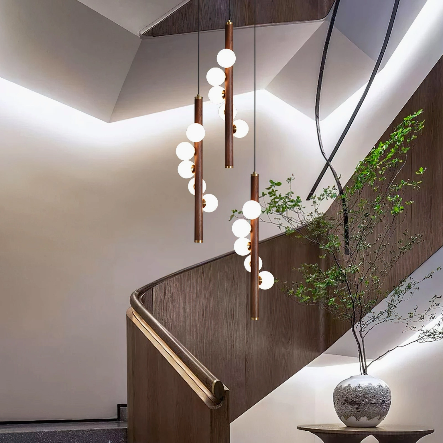 Multiple Miller pendant lights with varying rod lengths on modern duplex staircase, clustered glowing bulbs