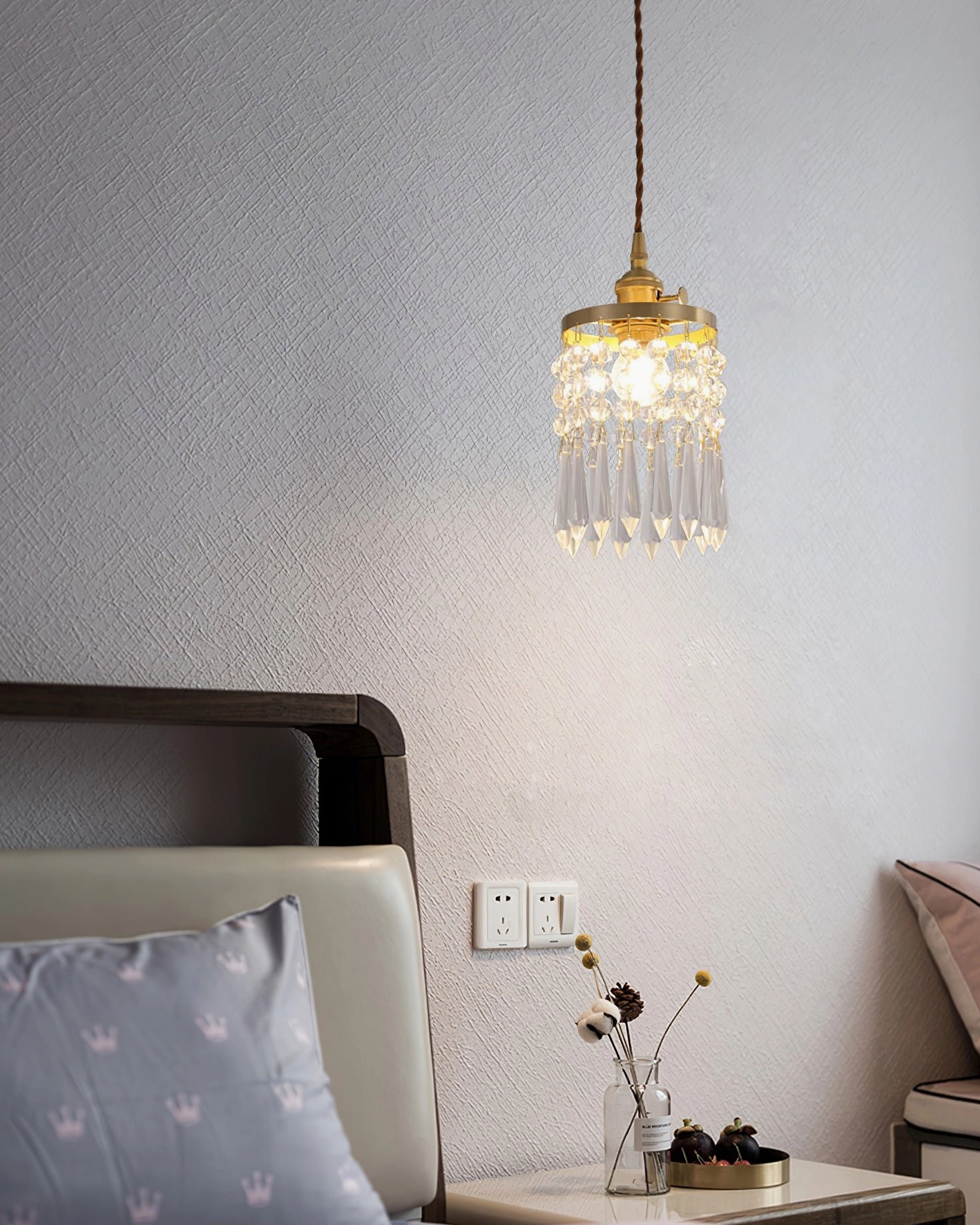 Mini crystal pendant lamp creating warm light in bedroom nightstand setting