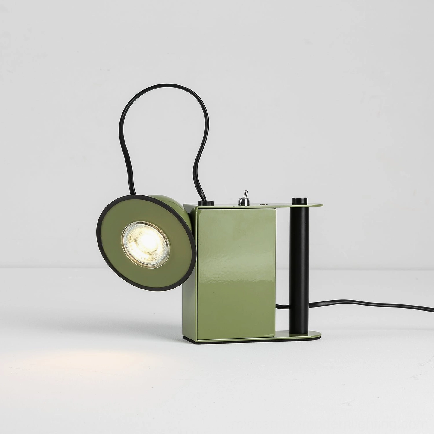 Green Minibox compact task lamp, side profile with illuminated spotlight, light spill detail, studio backdrop