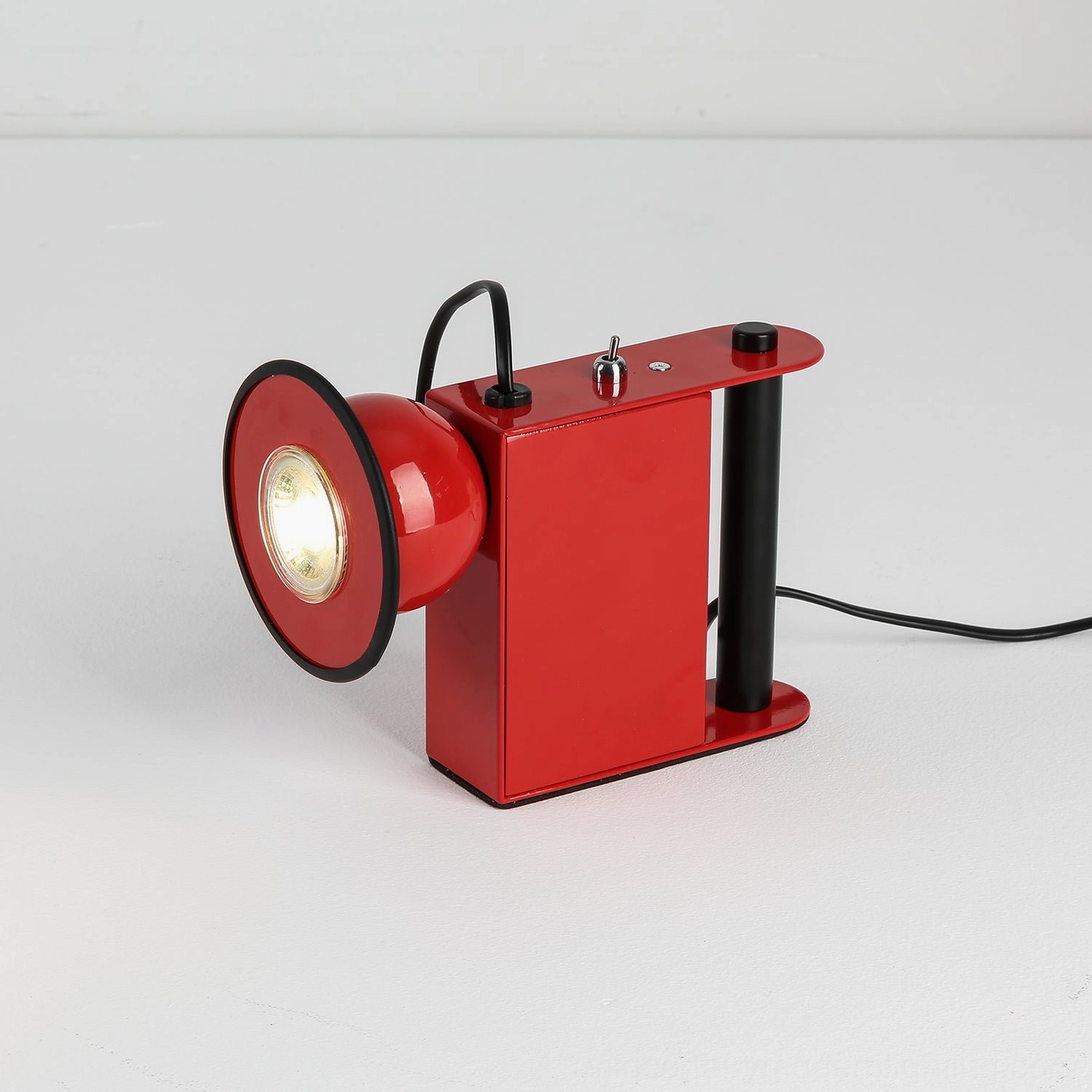 Red Minibox table lamp, studio angle emphasizing sculptural form and magnetic spotlight attachment point