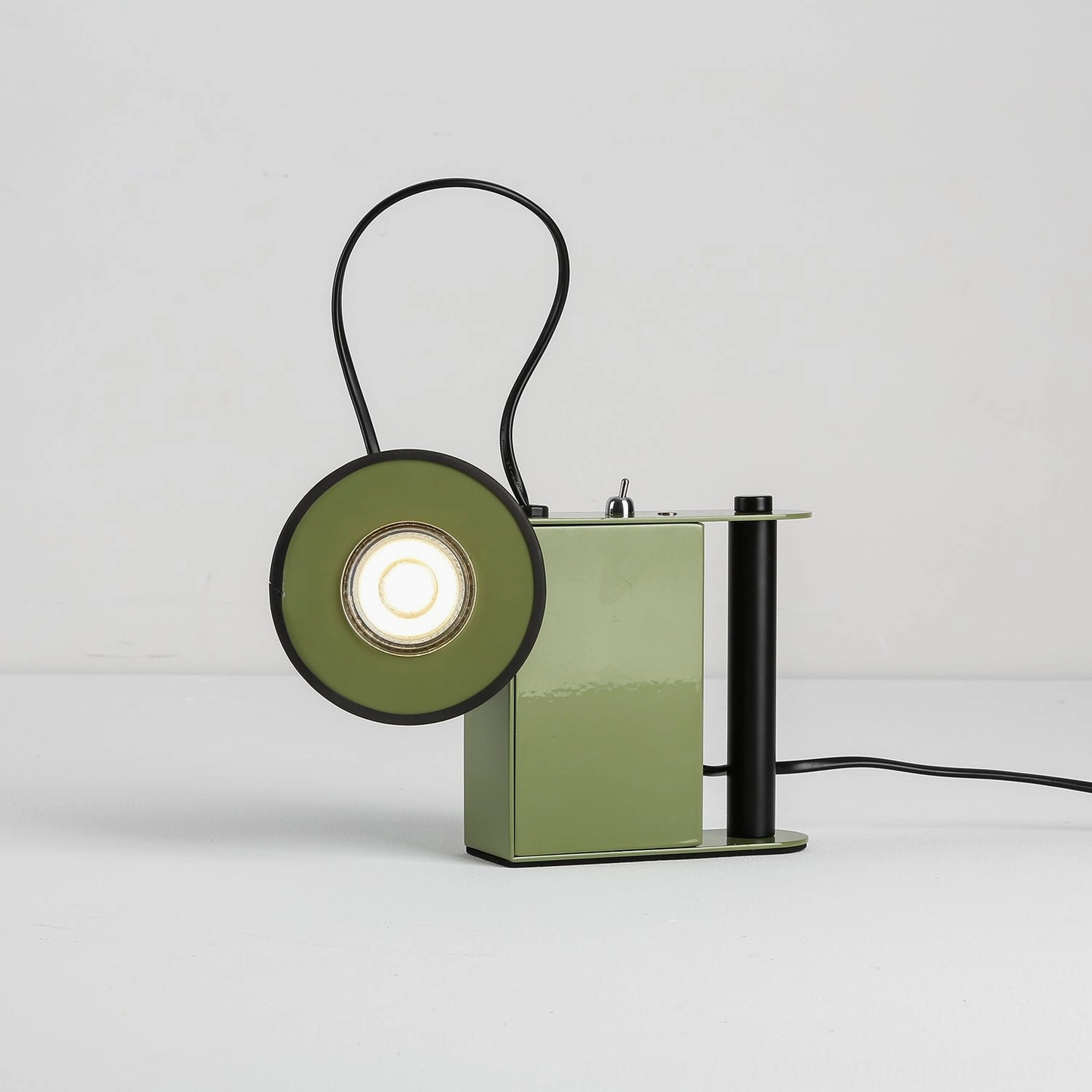 Sage green Minibox magnetic spotlight lamp, front view, unlit form showcasing geometric metal body and cylindrical handle