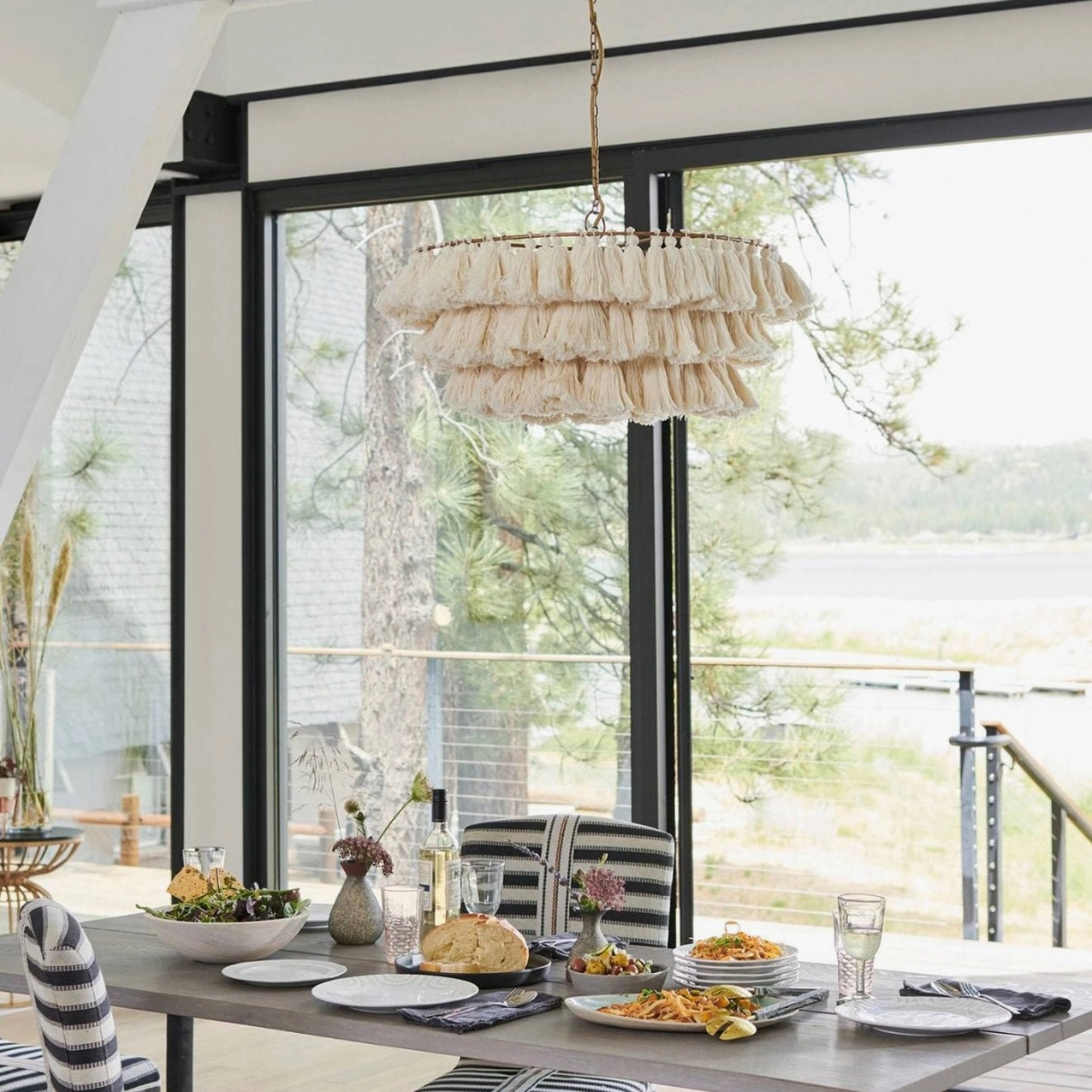 Cream fabric tassel chandelier with multiple tiers in sunlit dining area overlooking scenic lake view