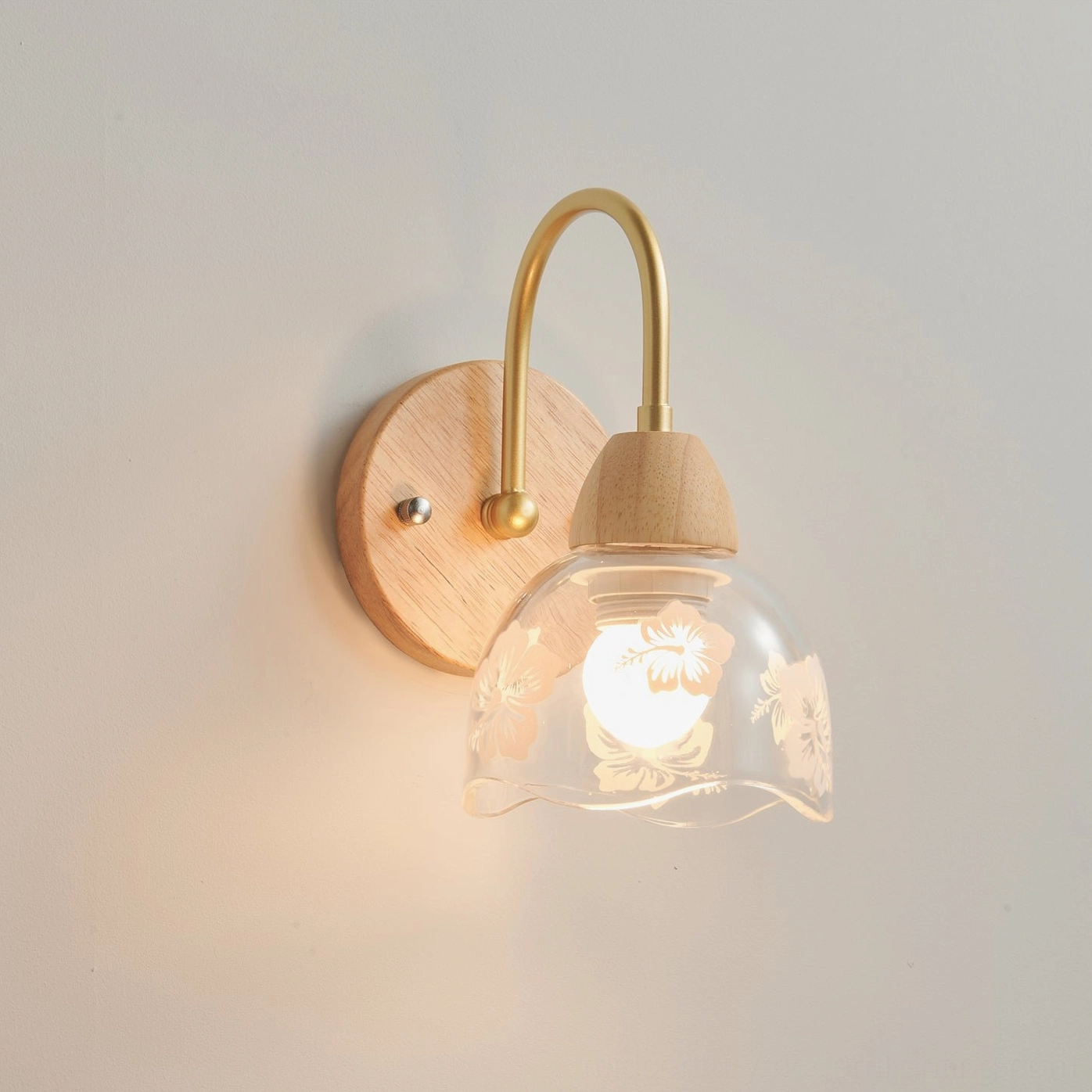 Floral etched glass wall sconce mounted in minimalist interior with neutral tones