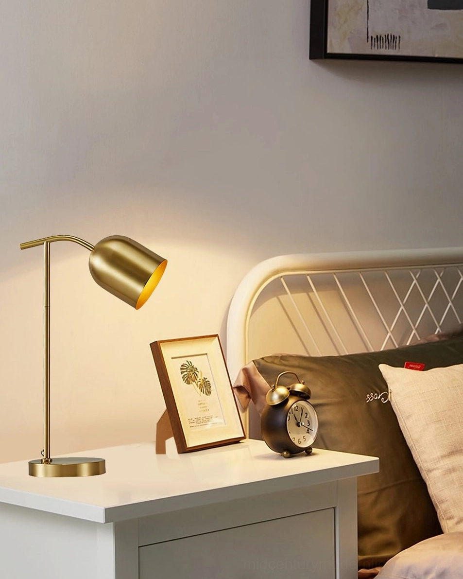 Minimalist brass gooseneck lamp on white wooden nightstand with framed artwork and alarm clock - bedroom design inspiration