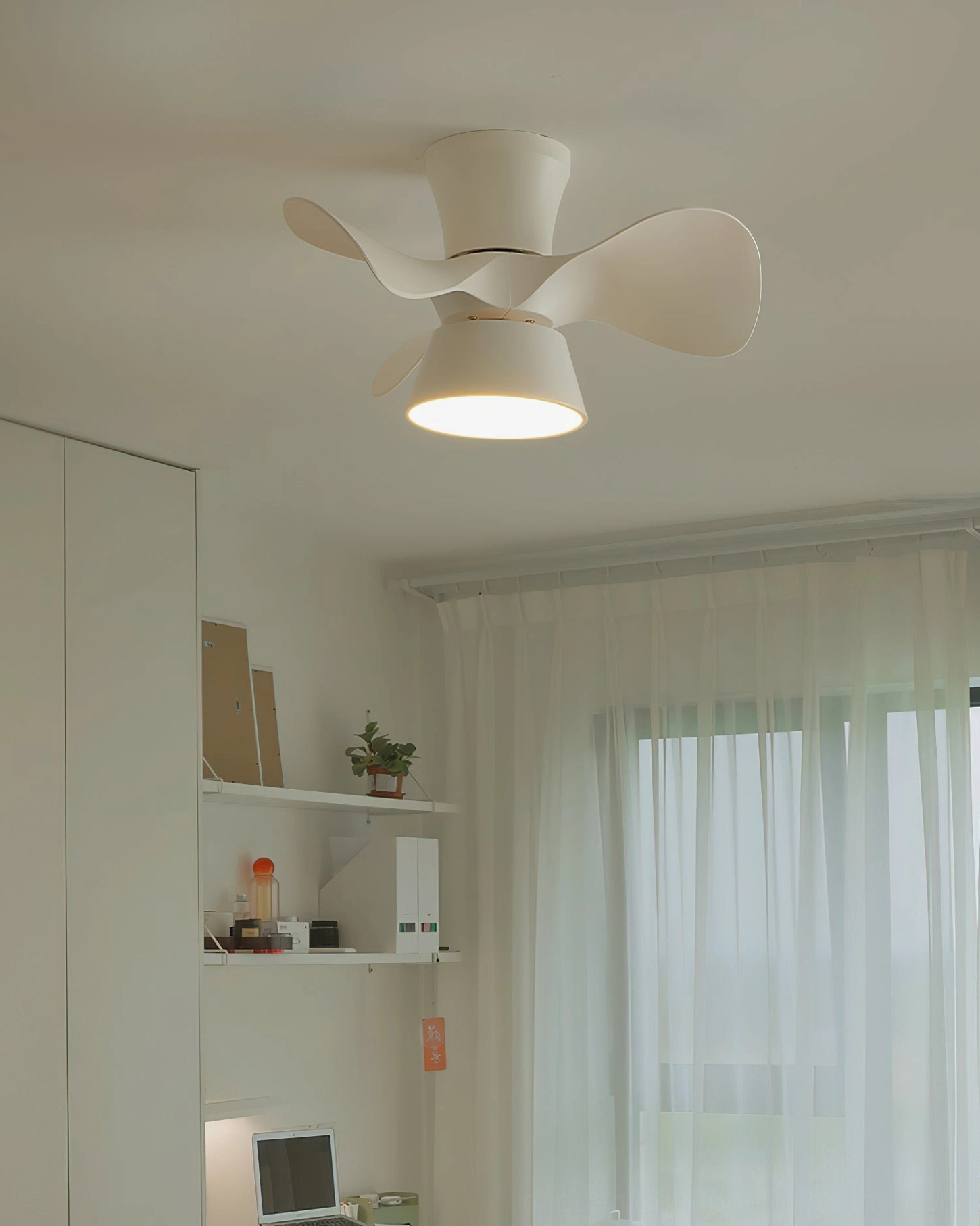 All-white minimalist three-blade DC ceiling fan light activated in modern study interior with shelving and soft natural light