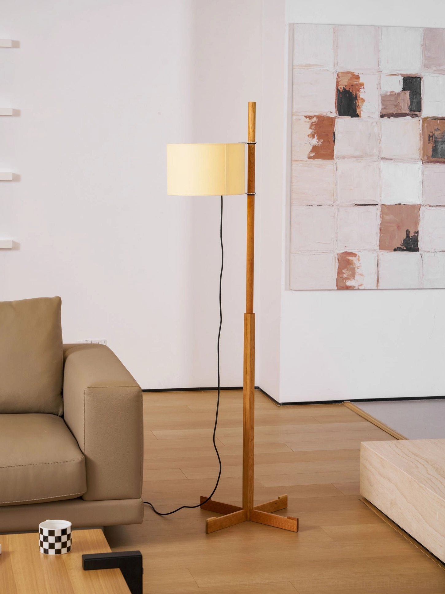 Wooden floor lamp creating ambient lighting in neutral-toned modern living room with wall art