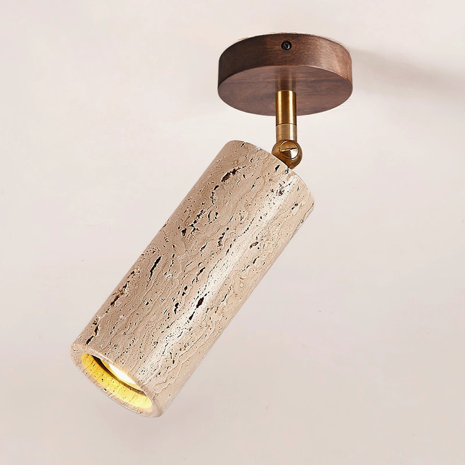 Detail view of Mireille travertine ceiling light showing dark wood base, visible stone porosity, and brass adjustable joint mechanism