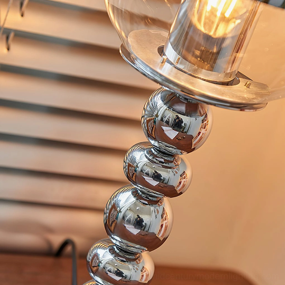 Close-up detail of chrome Mirrorball lamp exposed Edison filament bulb and beaded metal texture