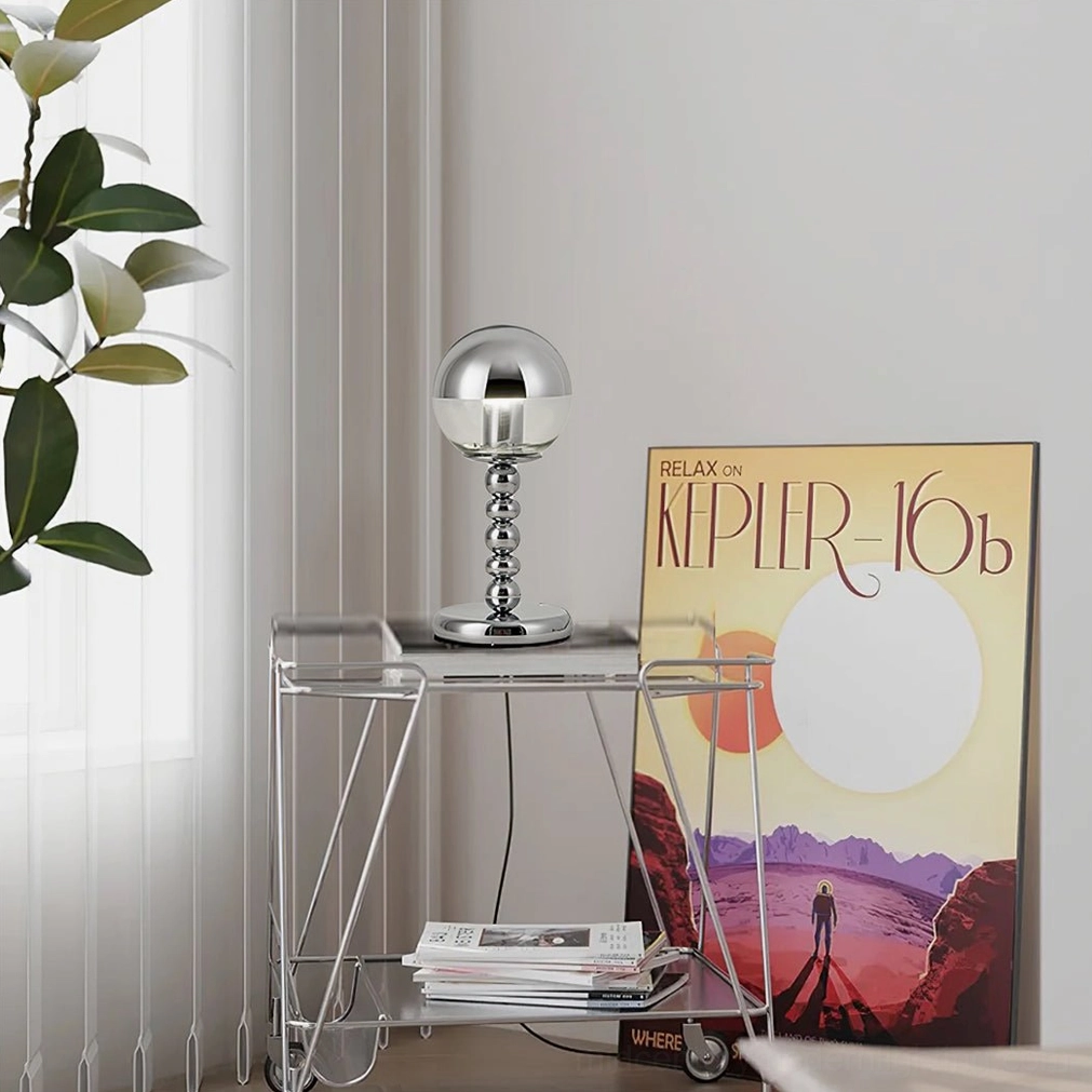 Geometric chrome sphere lamp on modern minimalist rolling metal side table in contemporary interior