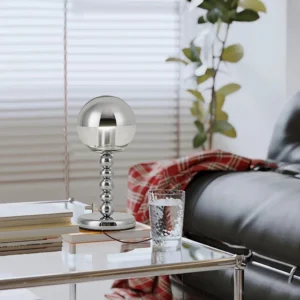 Mid-century modern chrome Mirrorball lamp displayed on stacked books with glass water on contemporary side table