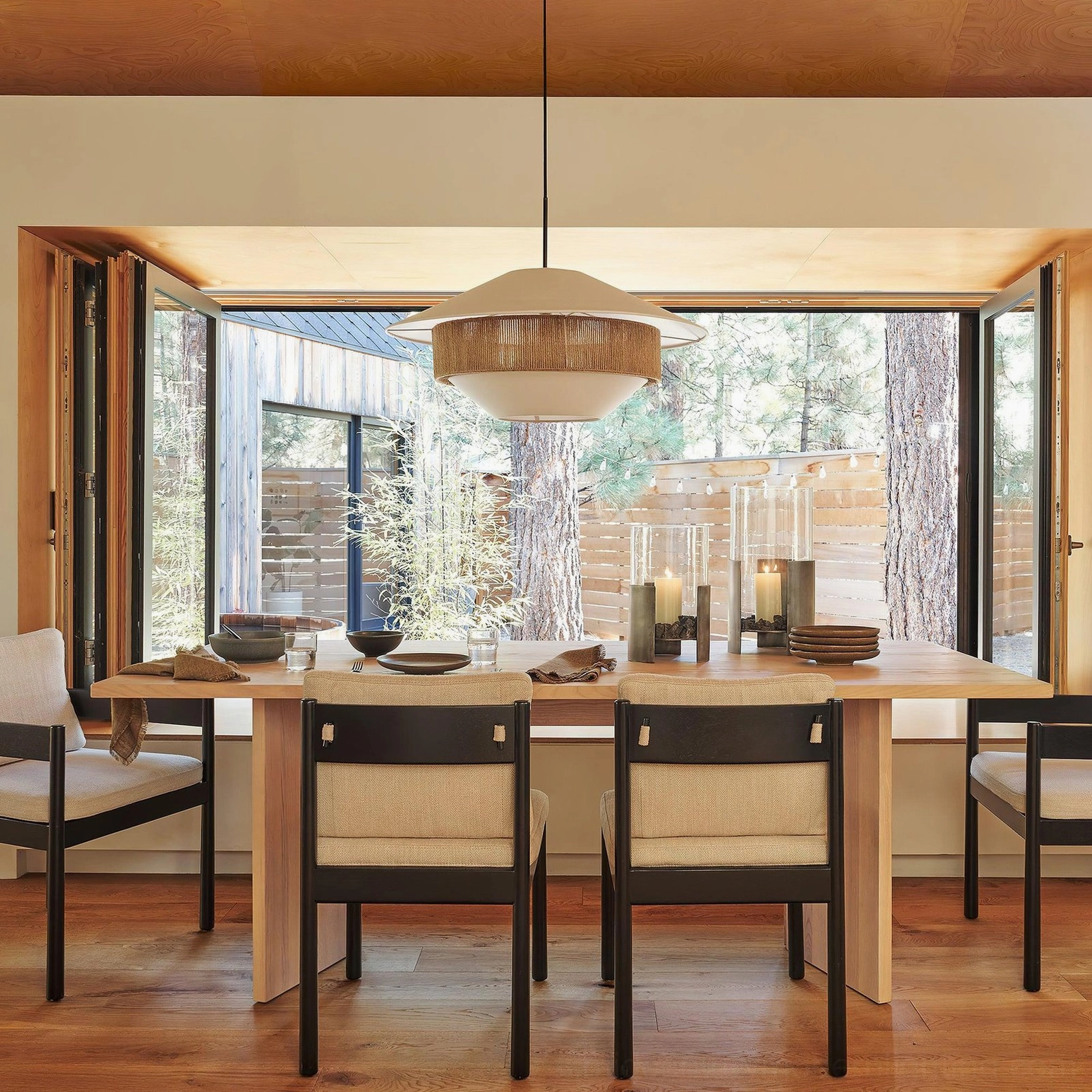 Mixed woven pendant light suspended over wooden dining table in warm rustic bohemian dining space