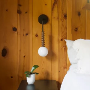 Mobo geometric wall lamp mounted on rustic wood panel wall in minimalist bedroom, bedside reading light at eye level