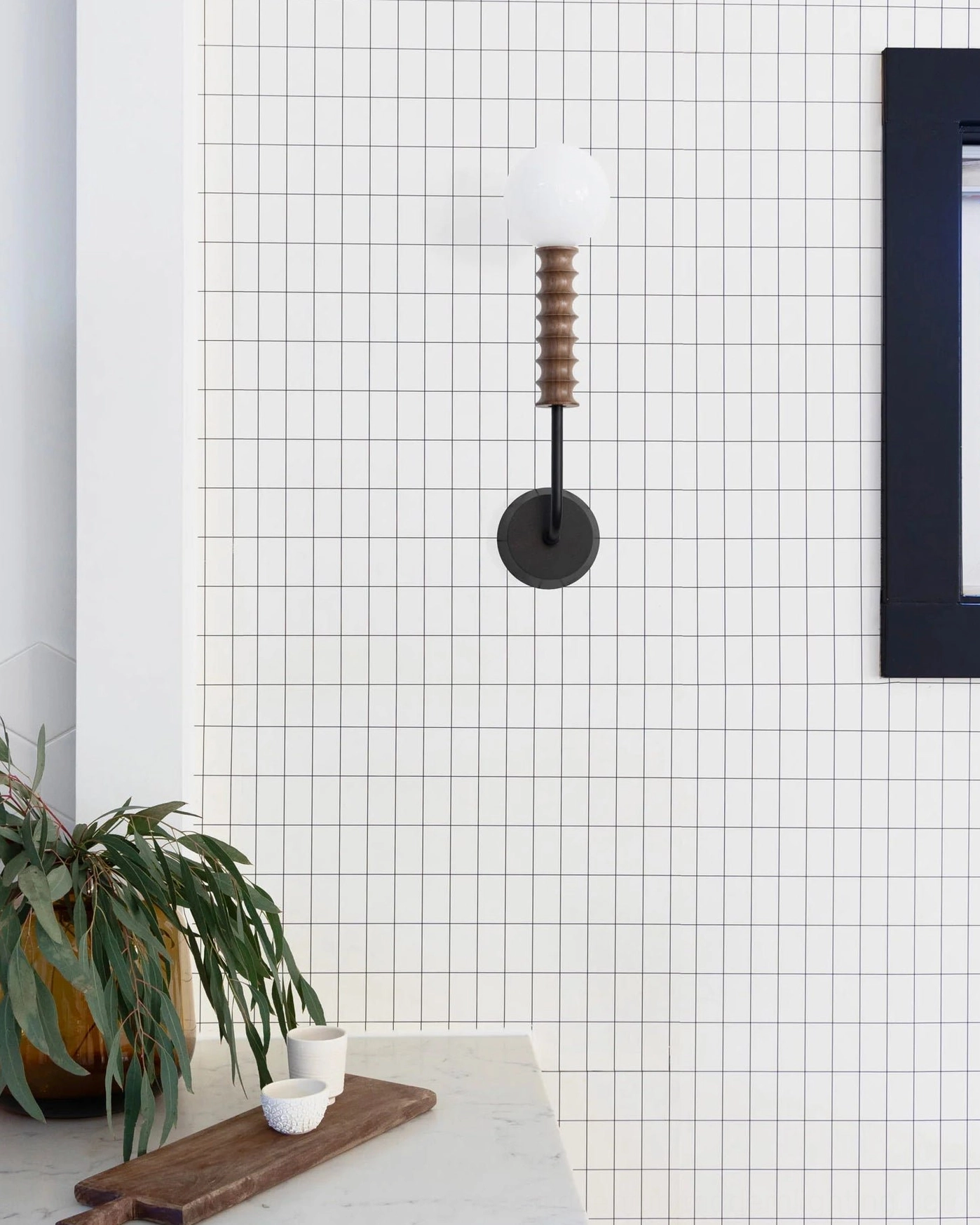 Mobo minimalist wall-mounted light fixture on grid tile bathroom wall, showing professional interior installation