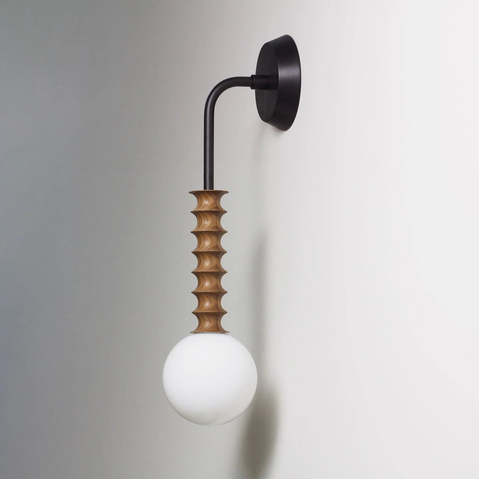 Mobo modern wall sconce close-up showing textured turned walnut wood stem and precision metal mounting hardware