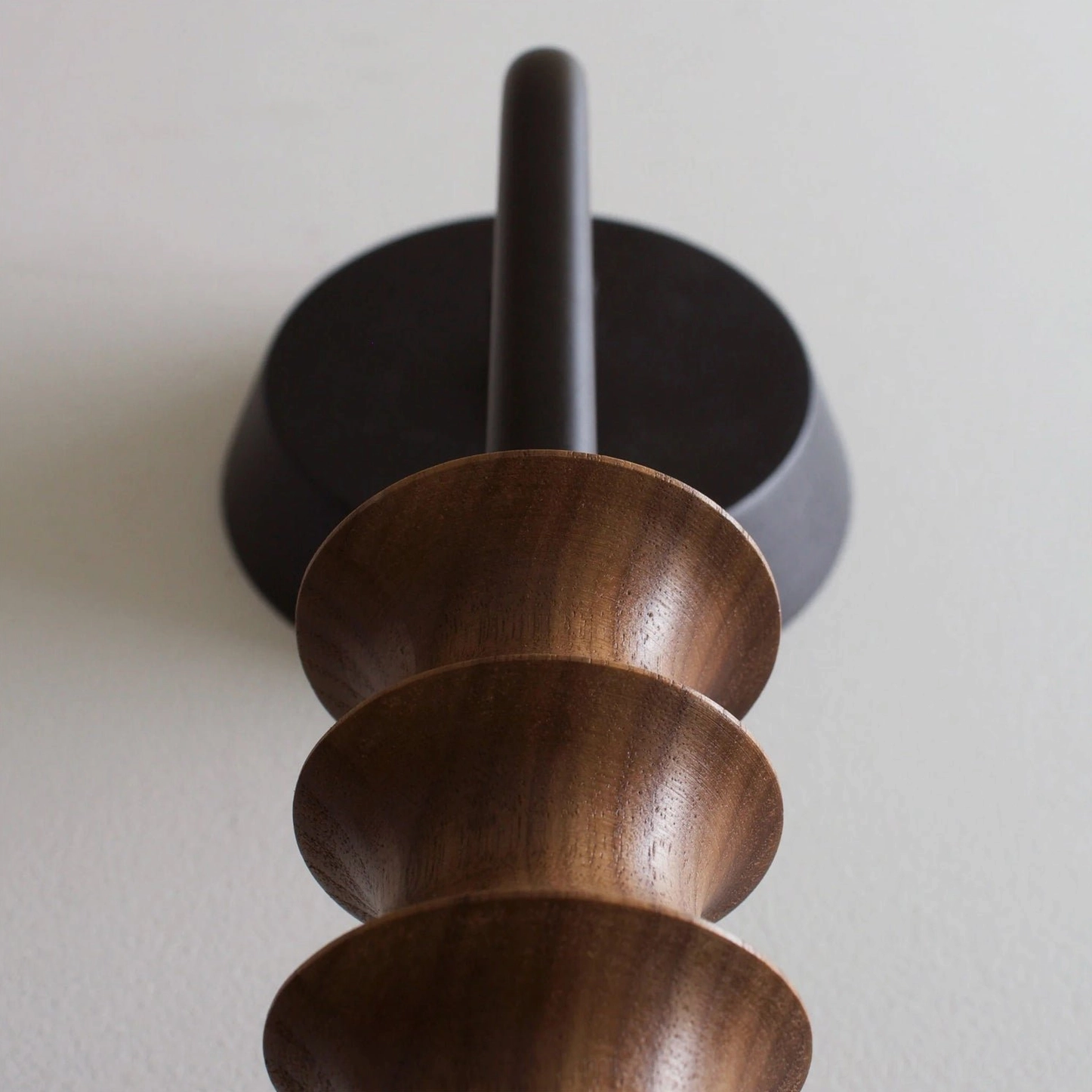 Overhead macro shot of Mobo wall lamp hardware and solid walnut wood turned details against grey wall