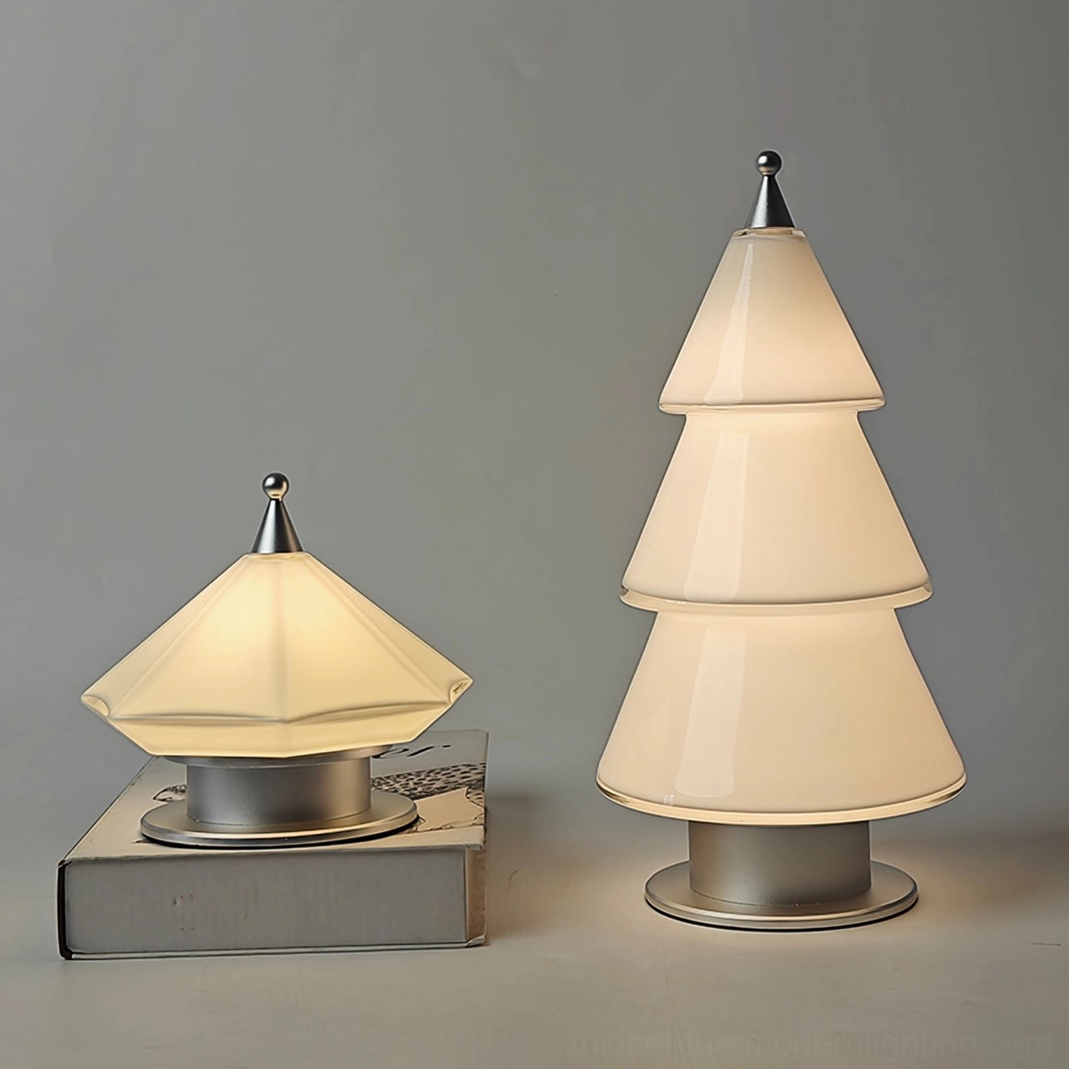 Two modern tiered cone table lamps with different heights compared side-by-side on neutral grey desktop backdrop
