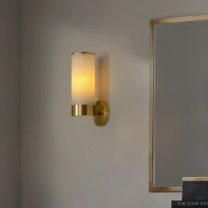 Modern alabaster wall sconce installed in luxury bathroom vanity lighting setup with mirror and warm ambient glow