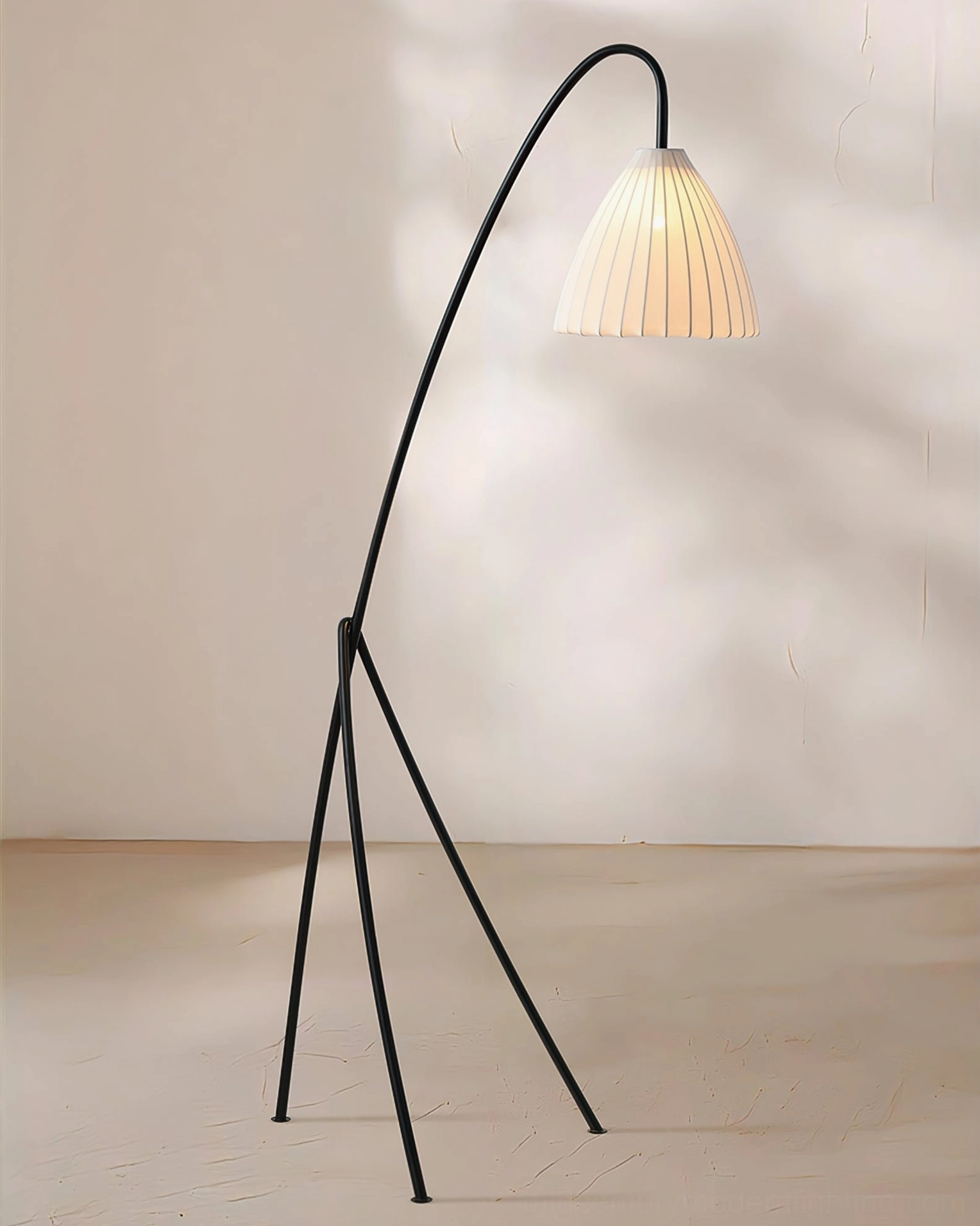 Modern soft warm arc tripod floor lamp in minimalist studio against neutral background, side angle shot showing contemporary lamp design