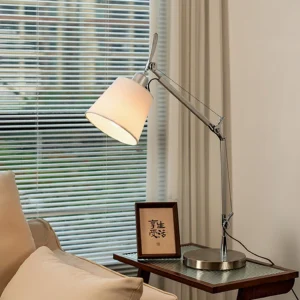 Contemporary adjustable table lamp lit in living room setting, showcasing warm light and sculptural design on side table with sofa backdrop