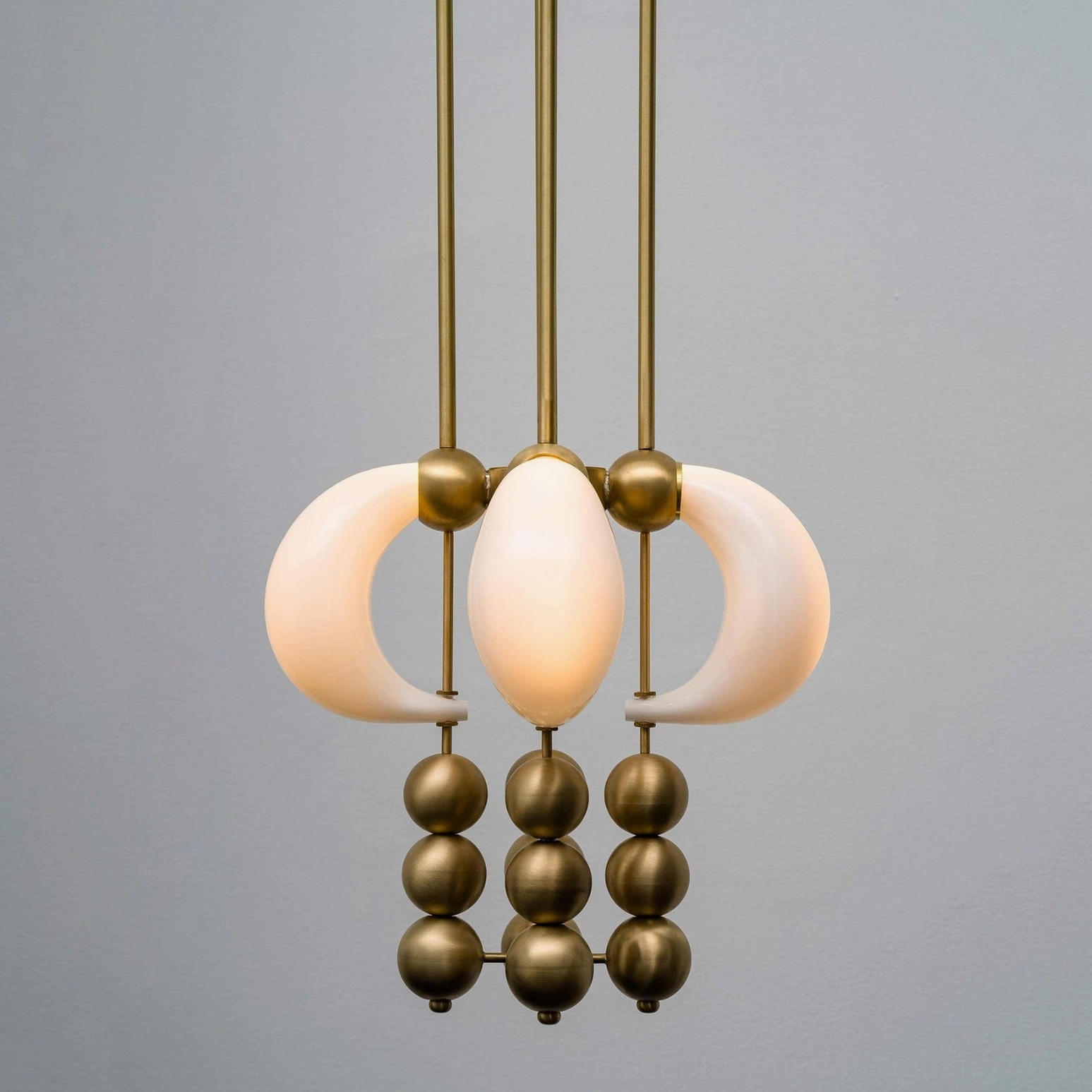 Modern bent glass pendant light with brass gold finish - front view sculptural chandelier against gray background