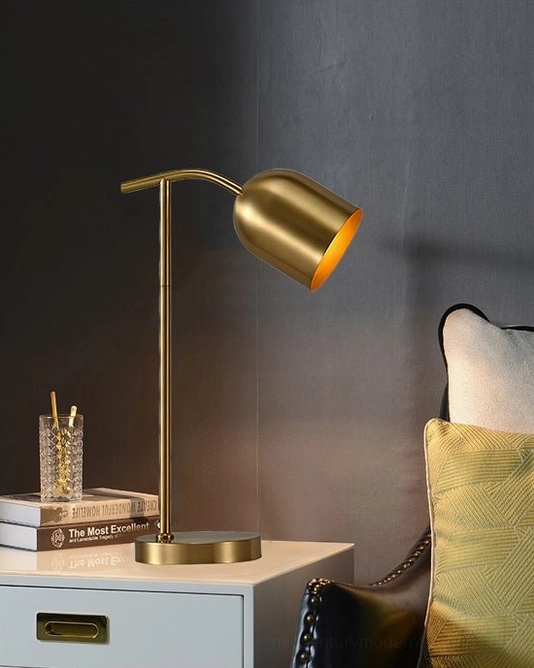 Modern brass gooseneck lamp on light gray nightstand with books and glass decorative objects - bedroom accent lighting