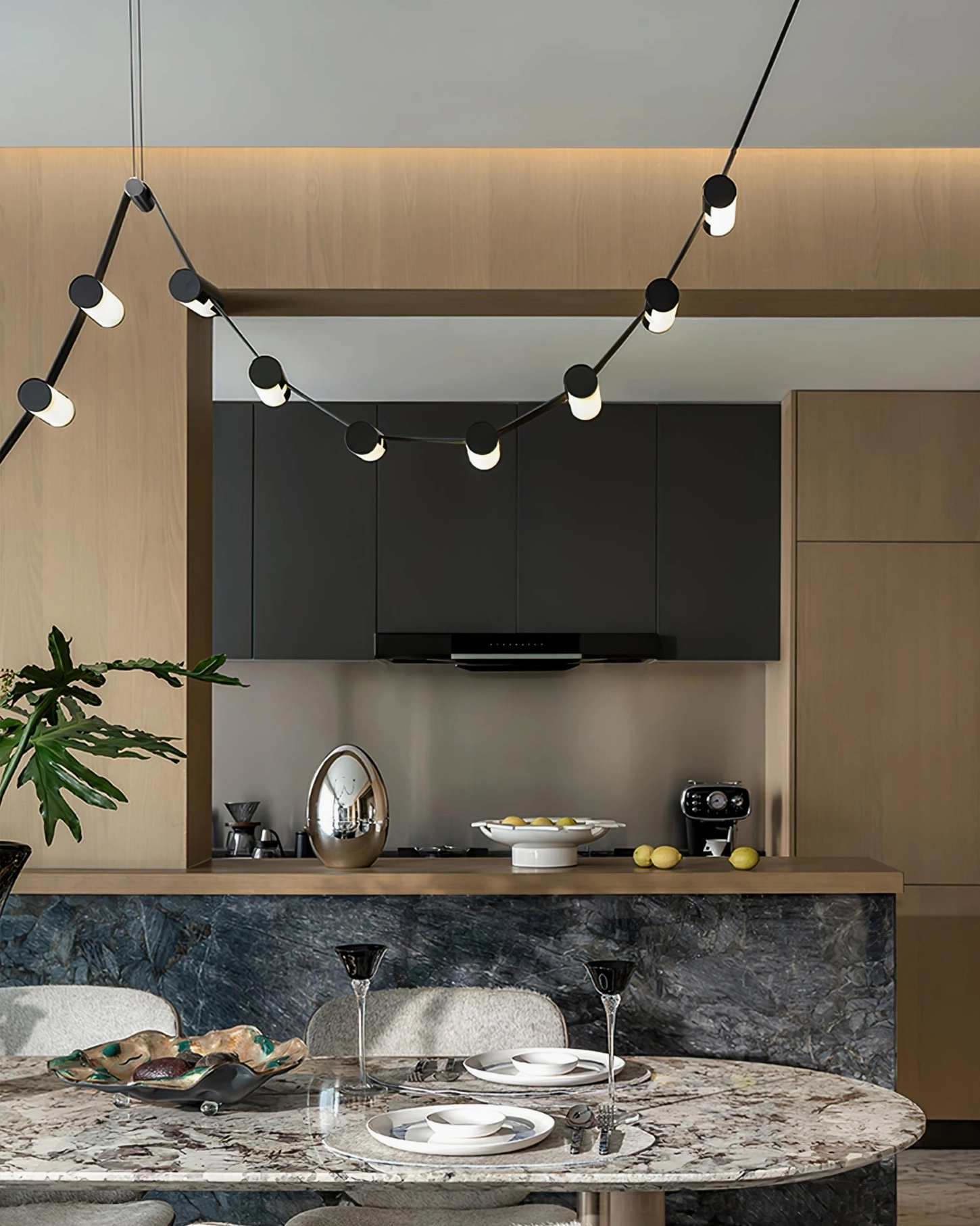 Sculptural wavy LED chandelier in modern kitchen with black metal rod structure, eye-level side view