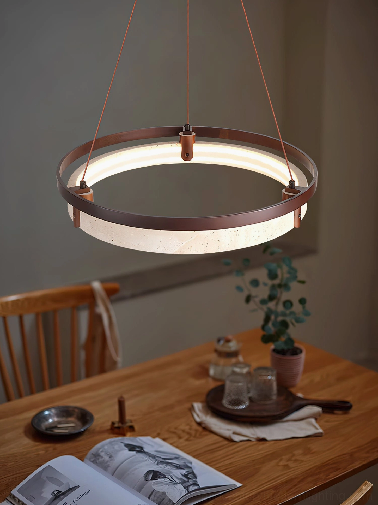 Modern dining space with travertine ring pendant light illuminating elegant table setup and neutral decor