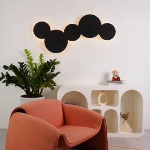 Matte black modern disc wall sconce mounted in contemporary living room with warm indirect illumination creating ambient atmosphere