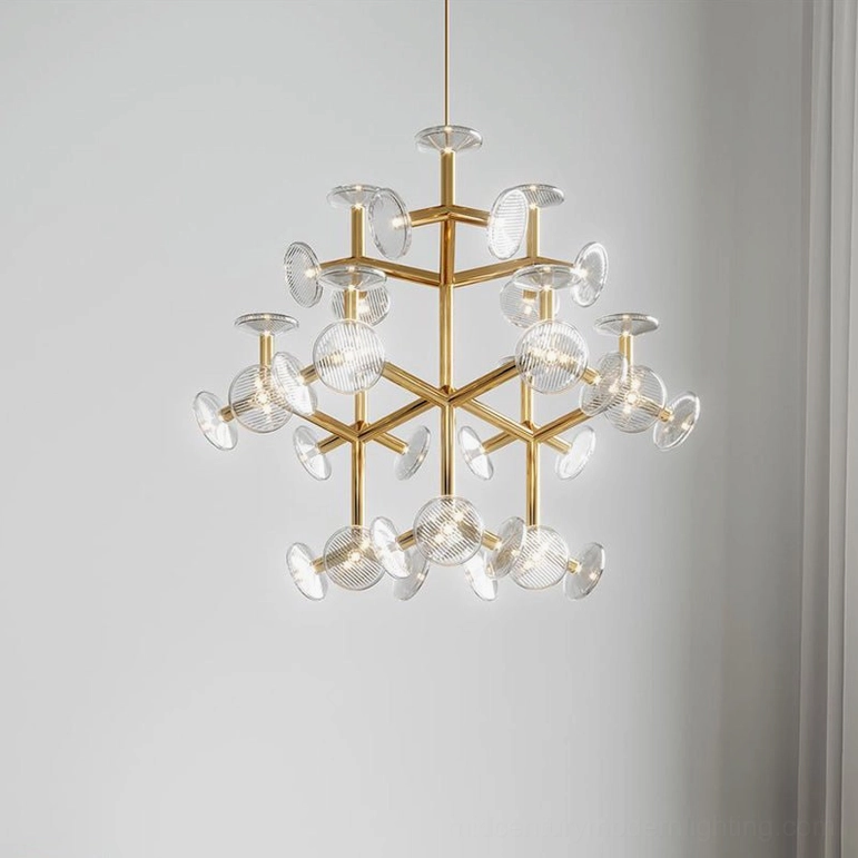 Symmetrical snowflake-style brass chandelier hanging in minimalist white interior design space