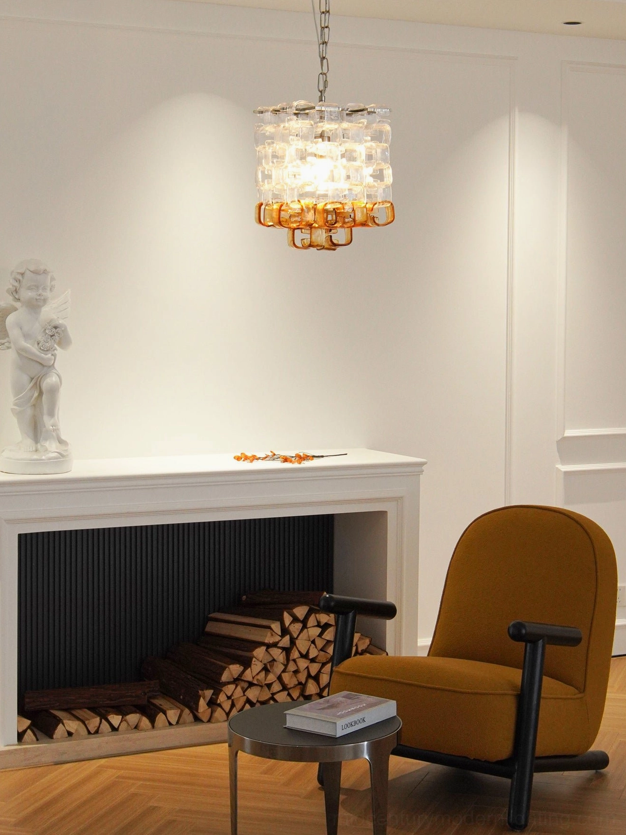 Elodie Murano glass chandelier suspended in elegant living room with fireplace, brown armchair and firewood stack, wide room view