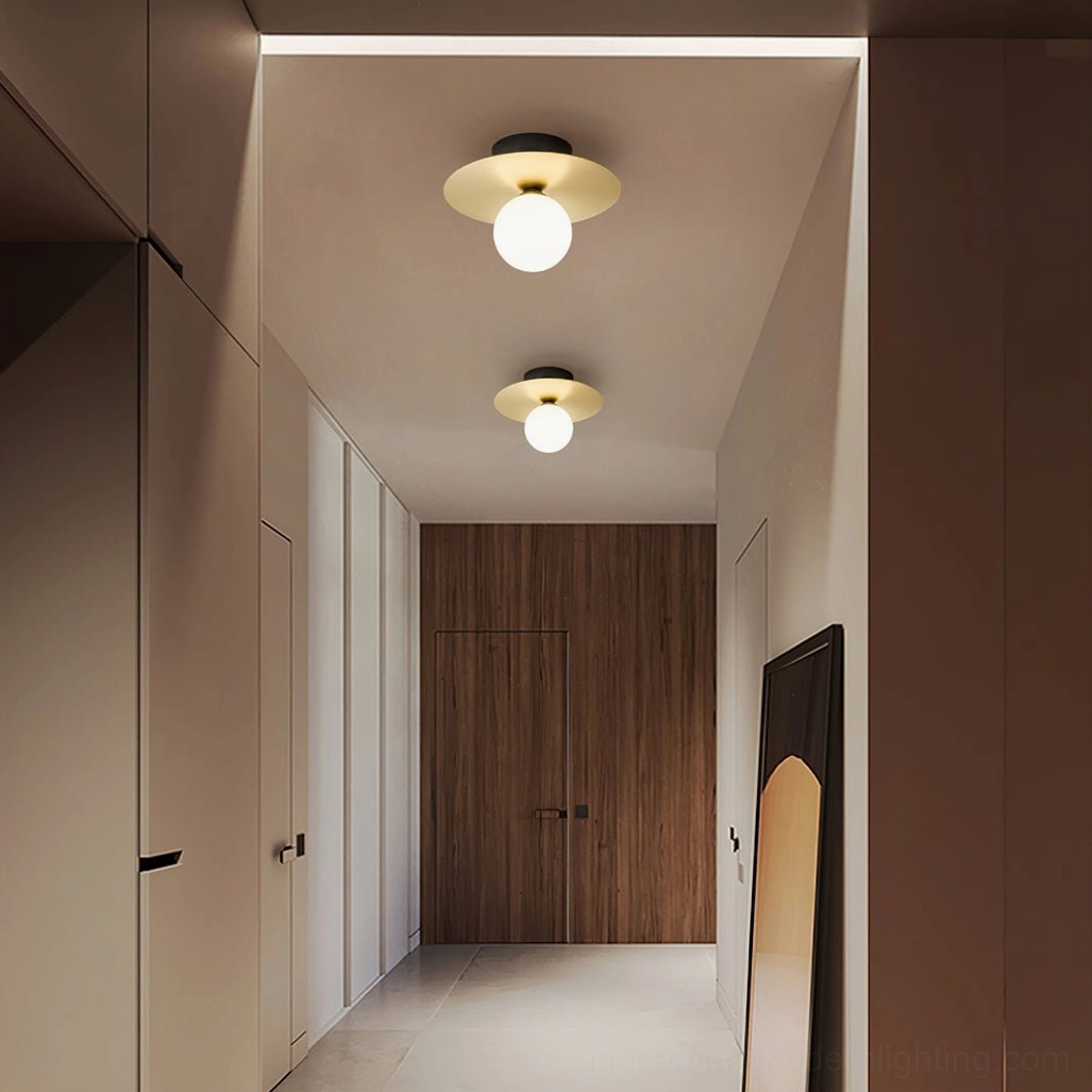 Warm brass disc and frosted glass wall lamp installed in modern residential hallway