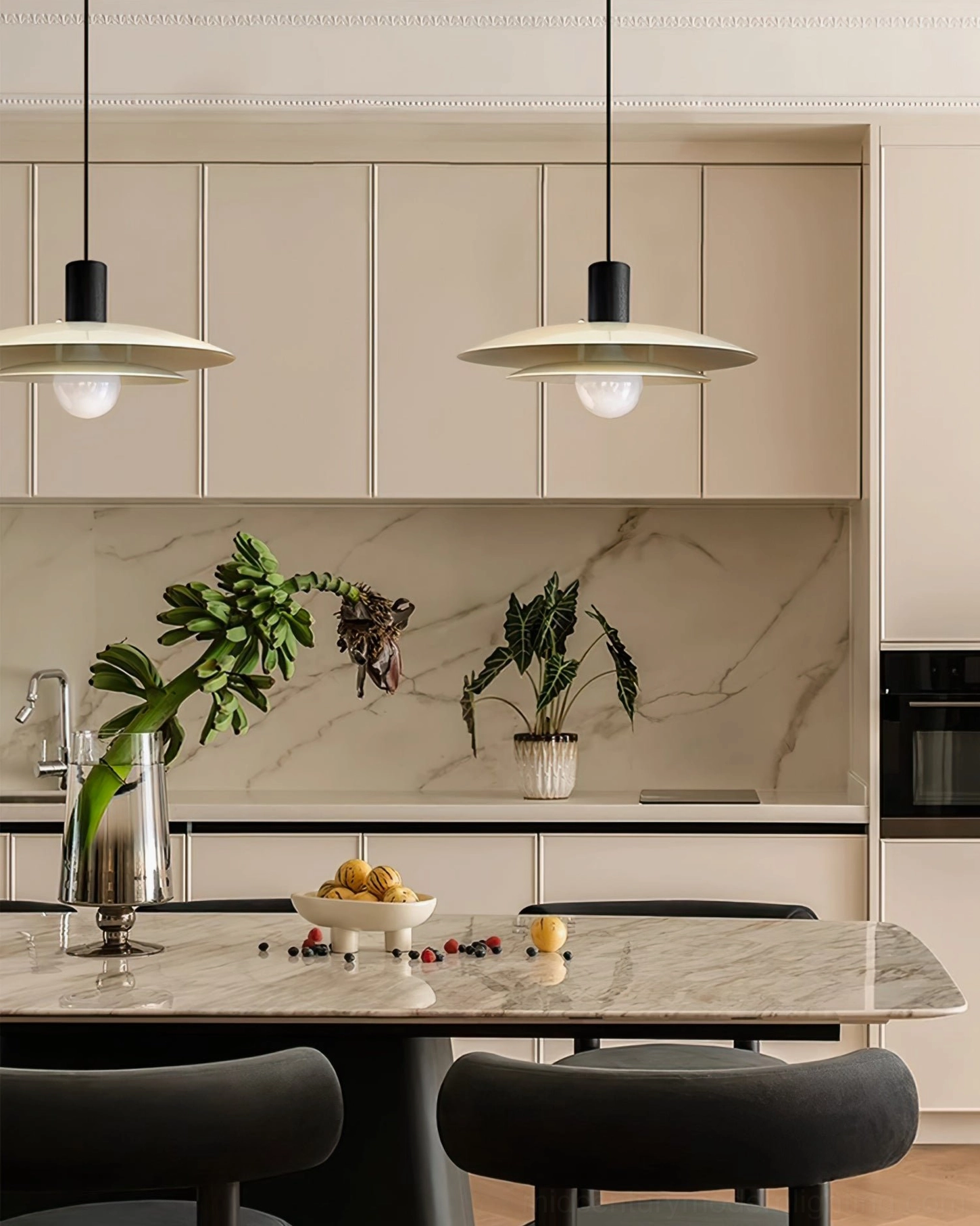 Dual pendant lights suspended above modern kitchen island with marble backsplash and minimalist design