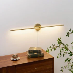 Brass gold minimalist wall sconce mounted above vintage wooden side table, side profile perspective