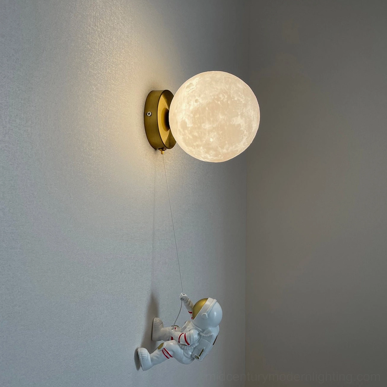 Modern moon wall sconce with silver-gold astronaut pendant in grey interior corner