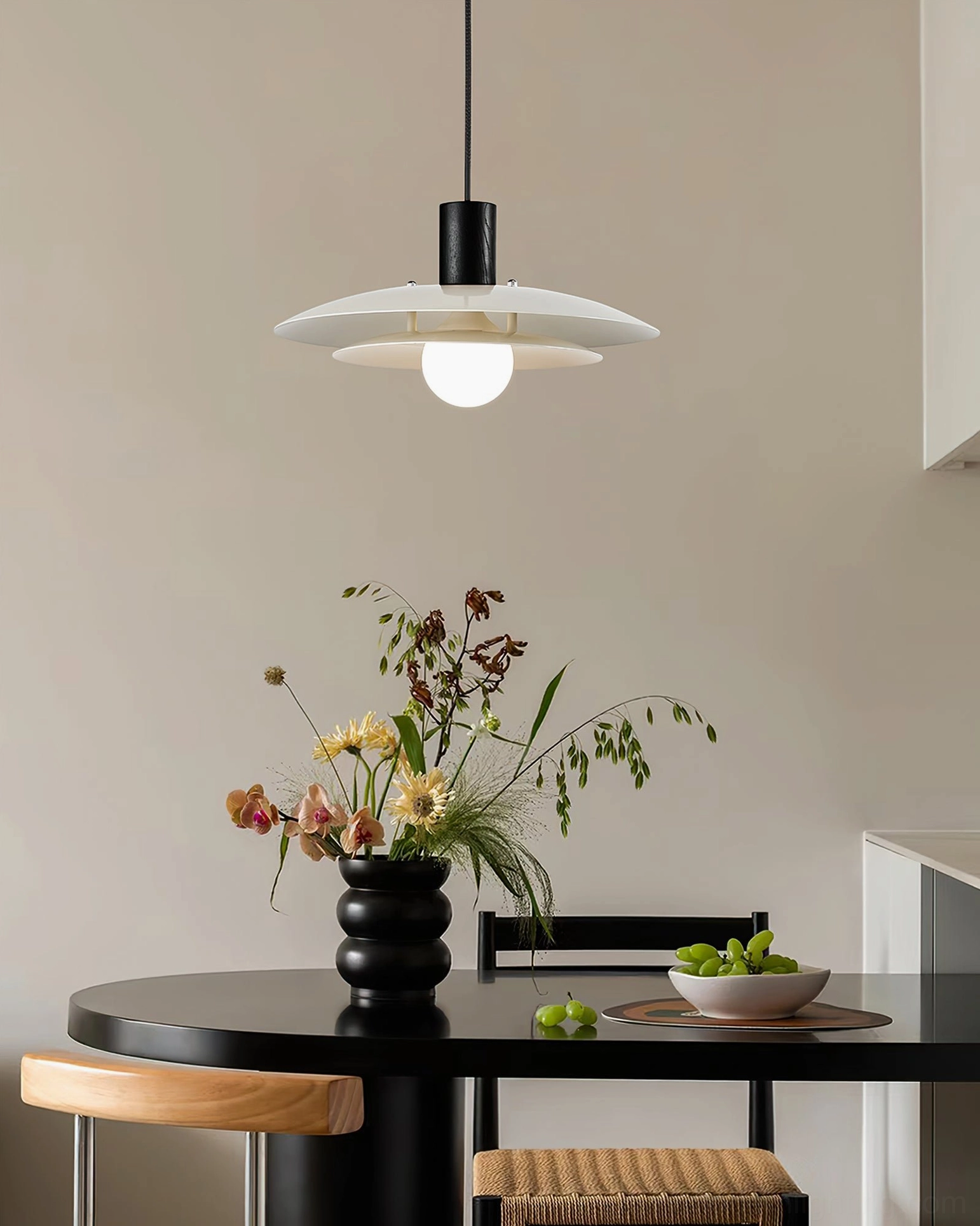 Modern pendant lamp in contemporary dining room with black wood and off-white finish suspended above dining table