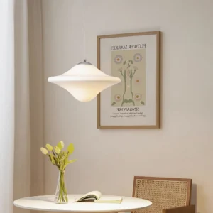 Modern pendant lamp suspended in minimalist dining nook with warm neutral lighting and wall art