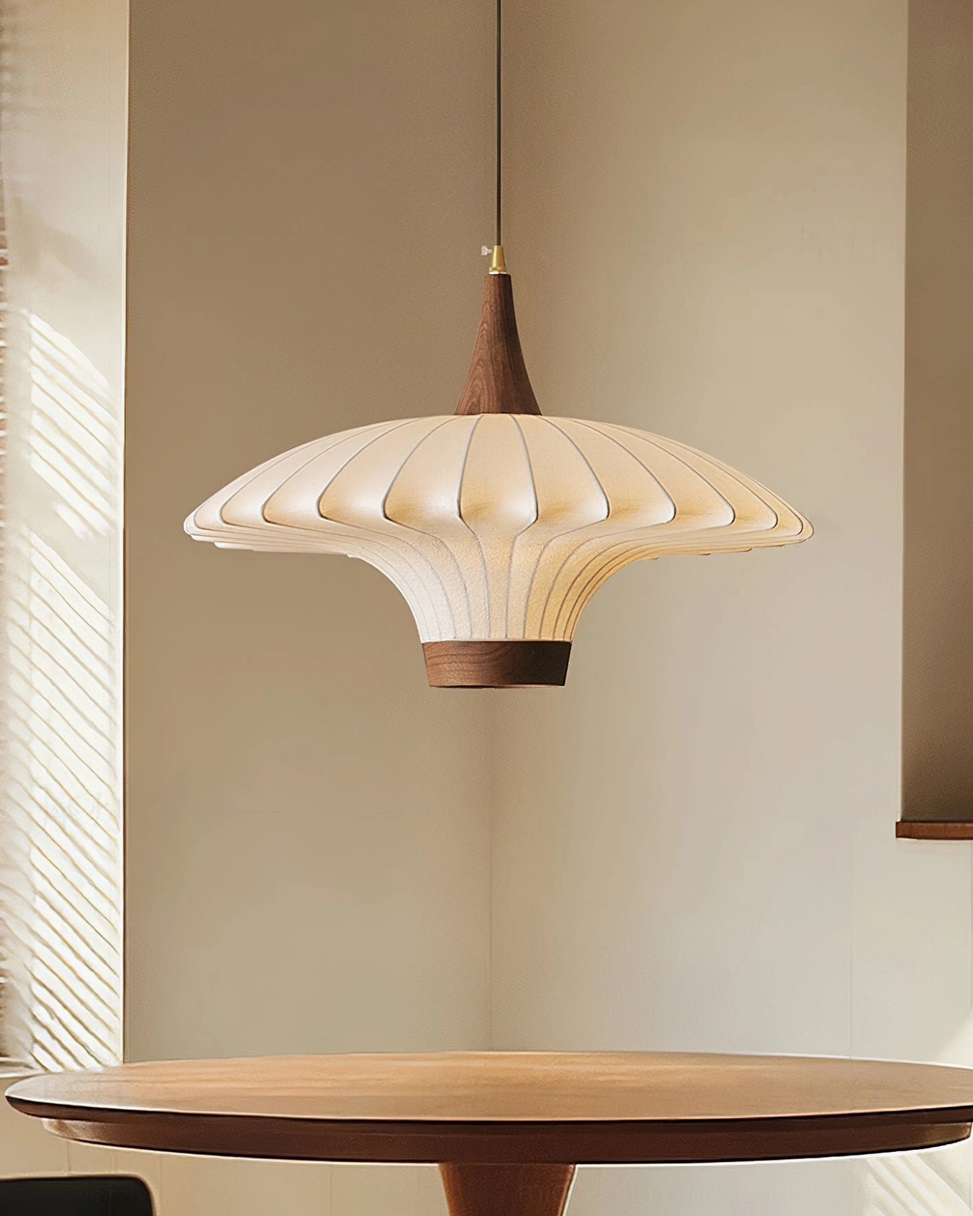 Contemporary pleated pendant light with flared umbrella design suspended above minimalist wooden table in modern interior