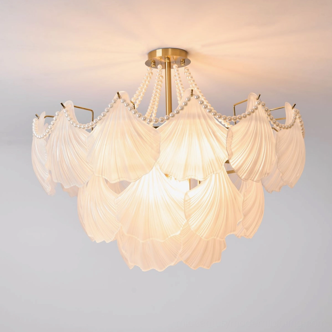 Modern scallop shell chandelier installation showing how frosted glass diffuses light in home interior