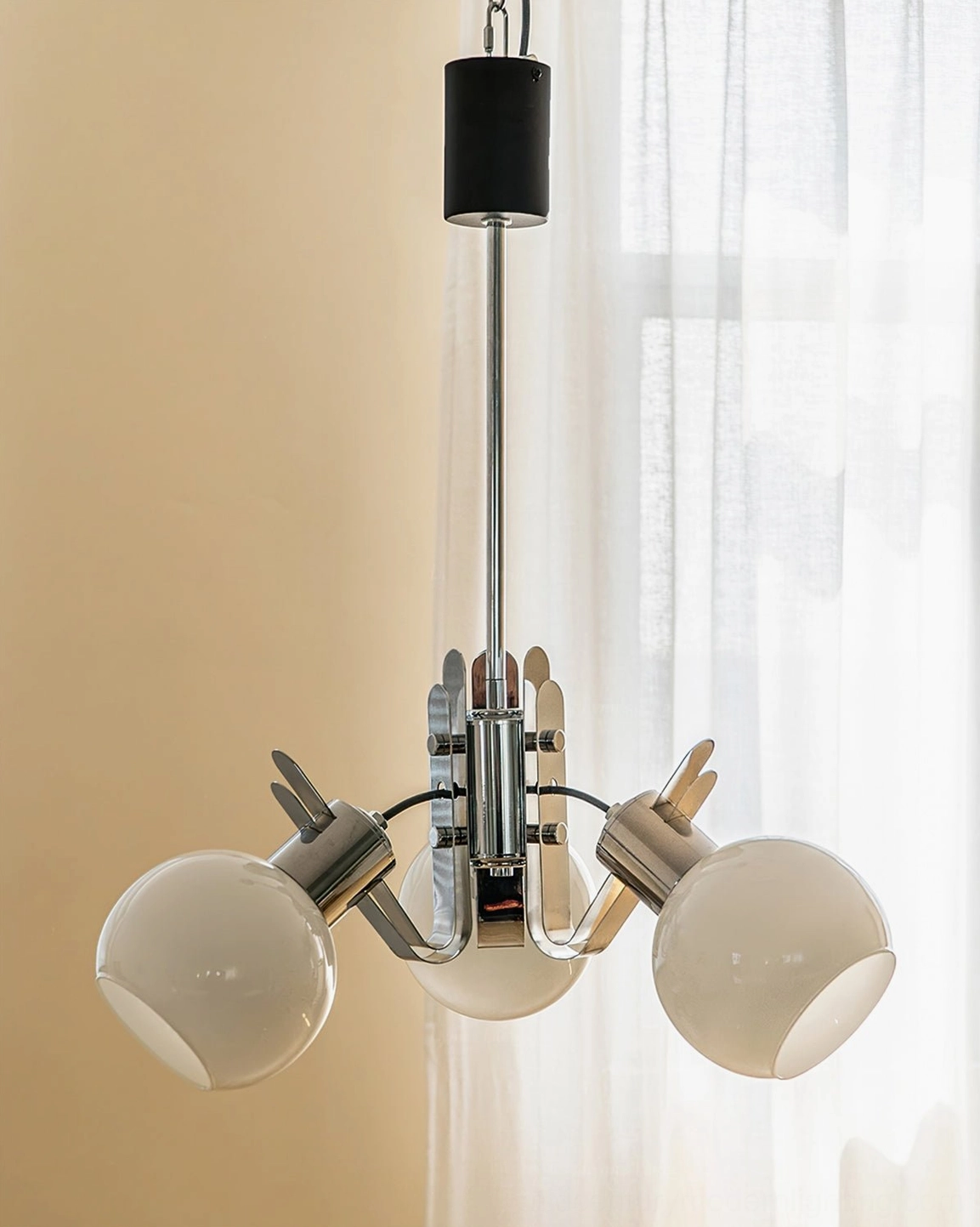 Modern three-head geometric glass chandelier with minimalist chrome frame in residential setting