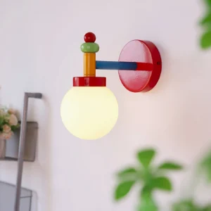 Illuminated colorful wall sconce casting warm light on home interior with green foliage backdrop