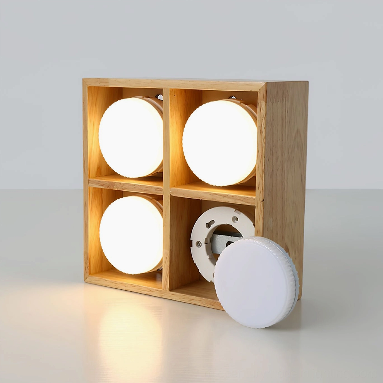 Disassembled modular wooden ceiling lamp showing replaceable white acrylic diffuser components on white background