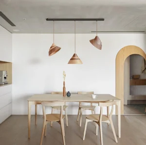 Multiple Moku pendant lights suspended in modern Nordic dining room, warm wood tones illuminated over dining table