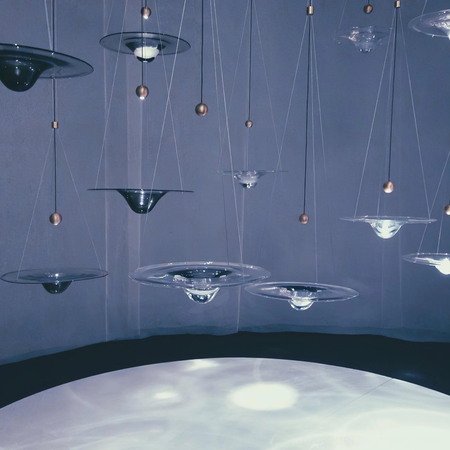 Momento pendant lamp collection in varied sizes displayed in contemporary exhibition space with warm ambient lighting