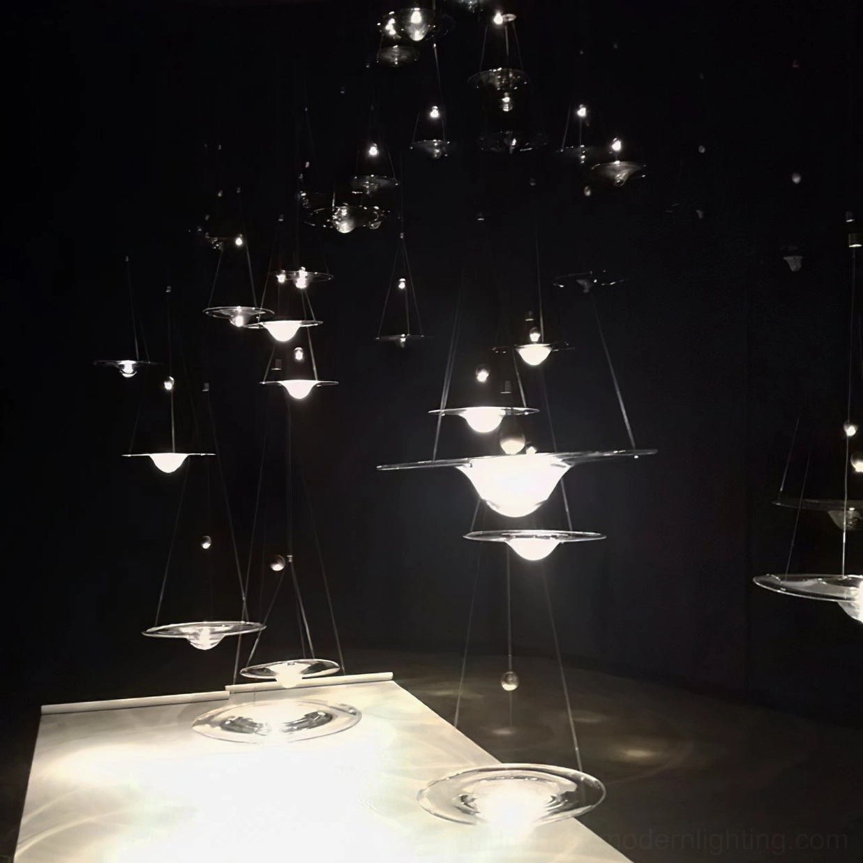 Multiple Momento hanging decorative pendant lamps in dark exhibition space with glowing warm light effect