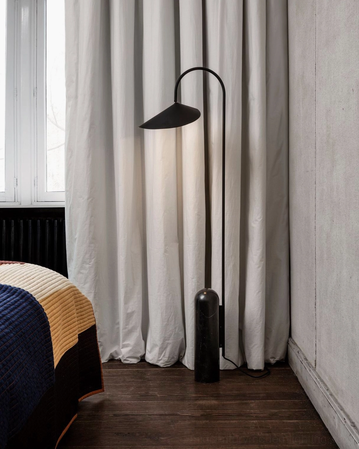 Mono floor lamp black finish in minimalist bedroom with bed radiator and ambient bedroom lighting