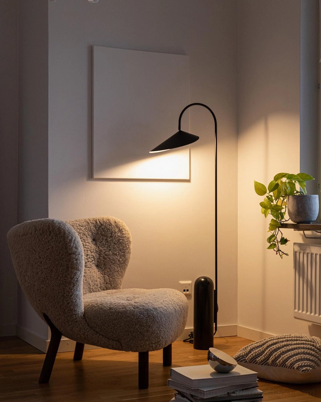 Mono floor lamp with black finish in warm-toned living room corner with tufted accent chair and radiator