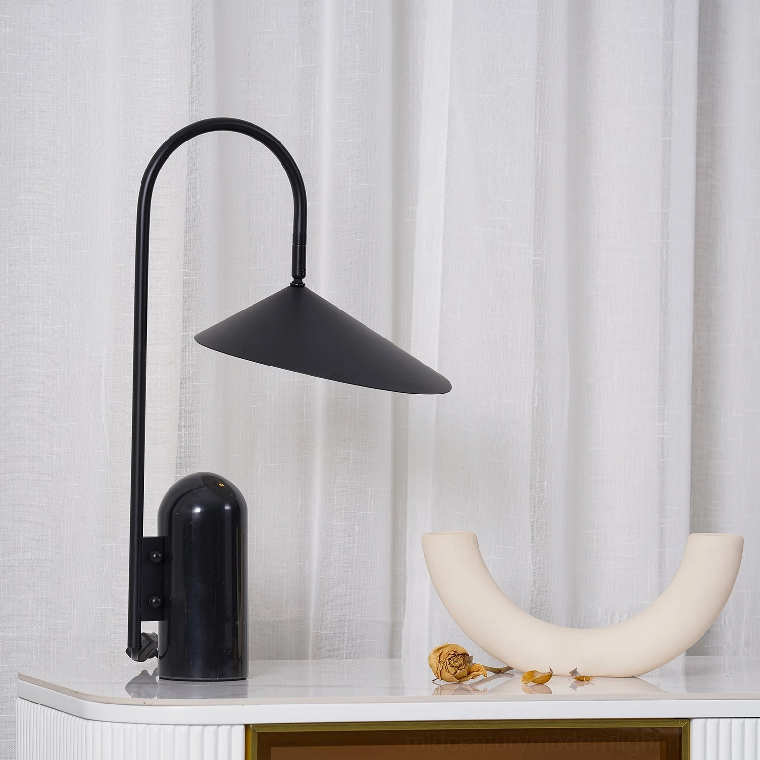 Architectural black marble base table lamp with graceful arched metal stem in modern home