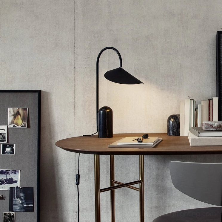 Contemporary black table lamp with graceful arch and marble base in studio or workspace