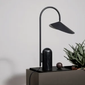 Minimalist black Mono table lamp styled on side table with green potted plants and decorative objects